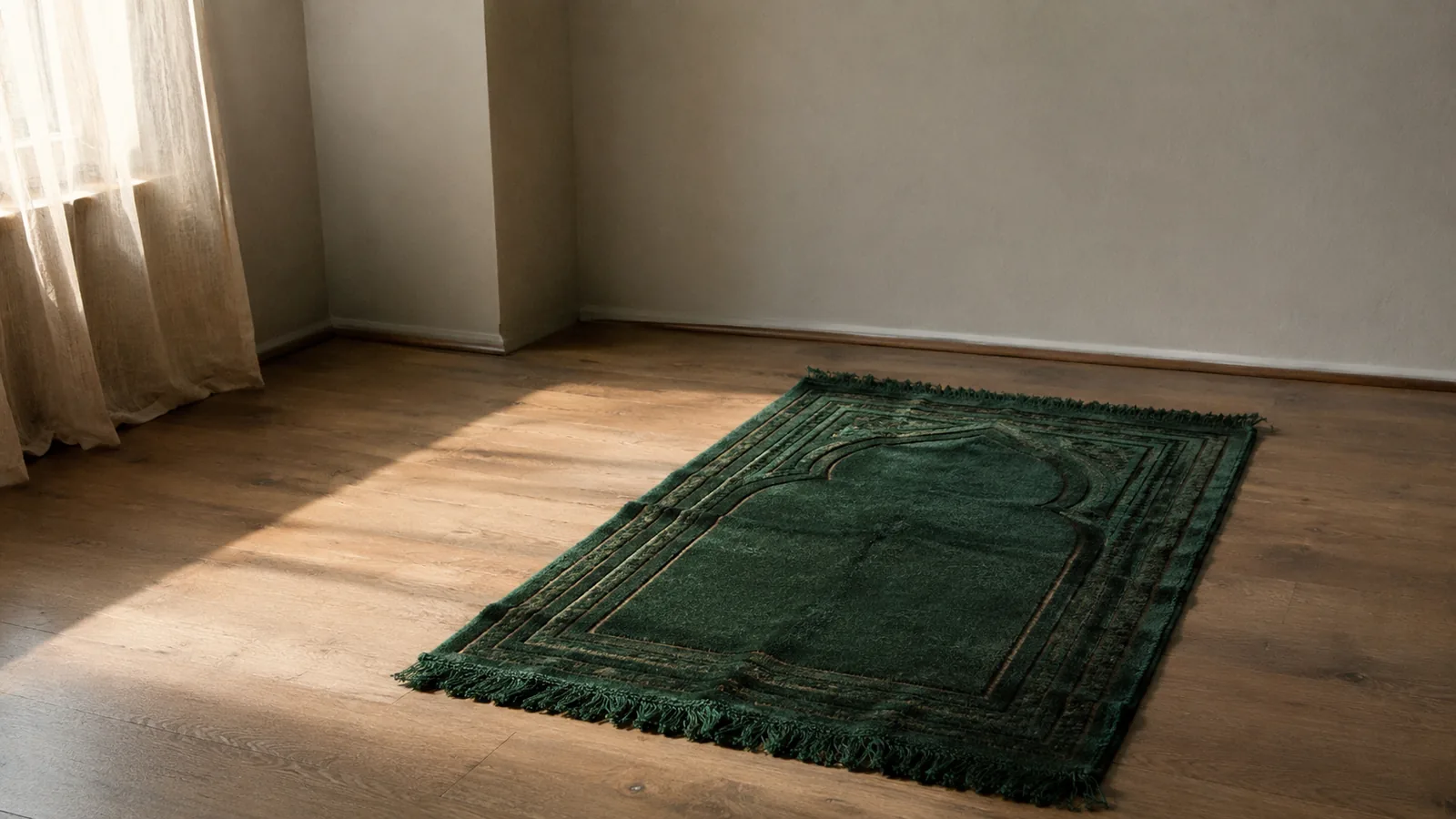 An empty room at first light with a green prayer mat laid on a wooden floor, angled toward the Qibla, sunlight falling across the boards from a window